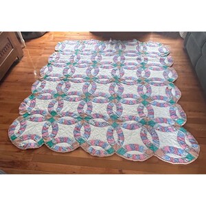 Colcha vintage feita à mão com estampa de alianças de casamento duplas, borda recortada e patchwork em tons pastel.