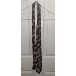 May include: A necktie featuring a repeating pattern of white baseballs with red stitching against a dark grey background. The tie is long and narrow, displaying multiple baseballs arranged in a dense, overlapping graphic print across the fabric.