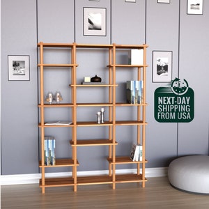 May include: A tall, wooden bookshelf with multiple shelves and open compartments. The bookshelf is made of natural wood and has a modern design.