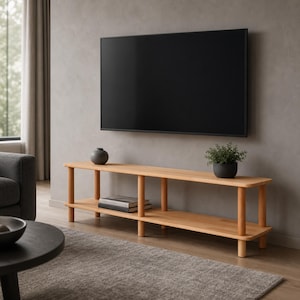 May include: A light-toned wooden media console featuring two long horizontal shelves supported by six cylindrical legs. A small dark gray vase sits on the top shelf, and a small potted green plant sits on the right side of the top shelf.