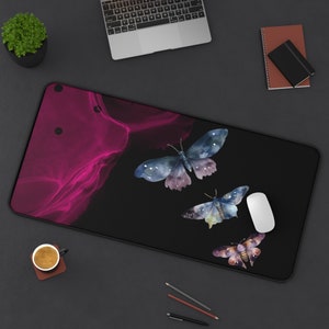 May include: A black and pink mousepad with a watercolor design of three butterflies. The butterflies are blue, purple, and yellow.