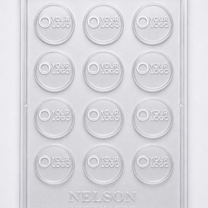May include: Clear plastic mold with twelve circular cavities, each embossed with "YOUR LOGO." The mold also features the text "NELSON NICE NACKS" at the bottom. Ideal for creating custom chocolates or candies.