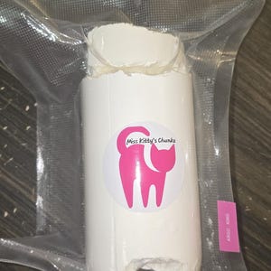May include: A white, cylindrical product is packaged in a clear plastic bag. A pink sticker with a cat logo and the text "Miss Kitty's Chunkz" is visible. A pink label with the text "ARGO KING" is also visible.