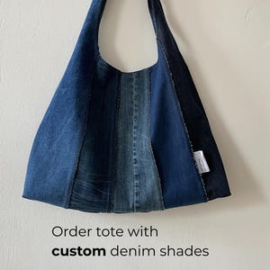 Peut inclure: Un sac fourre-tout en jean avec un design patchwork de différentes nuances de jean bleu. Le sac a une longue sangle et une forme triangulaire. Le texte "Order tote with custom denim shades" est visible en bas de l'image.