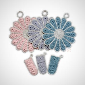 May include: Three flower-shaped crochet pot holders in pink, lavender, and blue with white centers and hanging loops, accompanied by three matching rectangular crochet handle covers in the same colors, all featuring a textured stitch pattern.