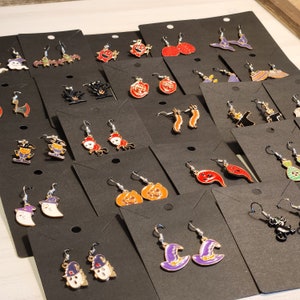 May include: Assortment of Halloween themed earrings on black card stock. The earrings feature various designs including ghosts, pumpkins, witches, bats, and more.