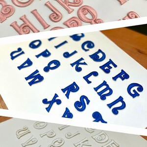 May include: Three sets of alphabet letters in different colors. The first set is pink, the second set is blue, and the third set is white. Each set has all 26 letters of the alphabet.