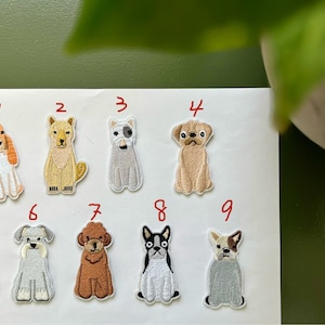 May include: Nine embroidered iron-on patches featuring different dog breeds. The patches are numbered 1 through 9. The dogs are a variety of breeds, including a pug, a schnauzer, a poodle, and a bulldog.