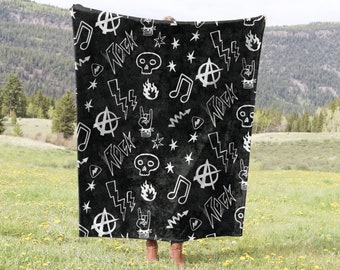 May include: Black and white throw blanket with a rock and roll theme. The blanket features musical notes, lightning bolts, anarchy symbols, skulls, and the word "rock" repeated throughout.