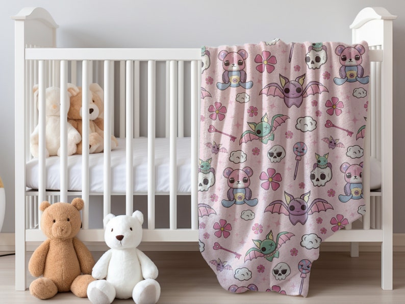 K&ouml;nnte beinhalten: Eine rosa Babydecke mit einem niedlichen Cartoon-Muster mit Flederm&auml;usen, Sch&auml;deln, Herzen und Blumen. Die Decke ist weich und kuschelig, perfekt f&uuml;r ein Babyzimmer.