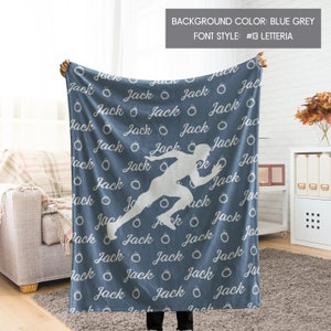 May include: A blue fleece blanket with a white silhouette of a runner and the name "Jack" repeated in a white cursive font. The blanket has a blue grey background color.