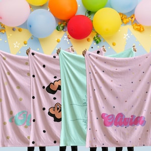 May include: Four pink and white blankets with different designs. The blankets have black polka dots, a heart, a hand with a plant, and the name "Olivia" in pink and purple letters.