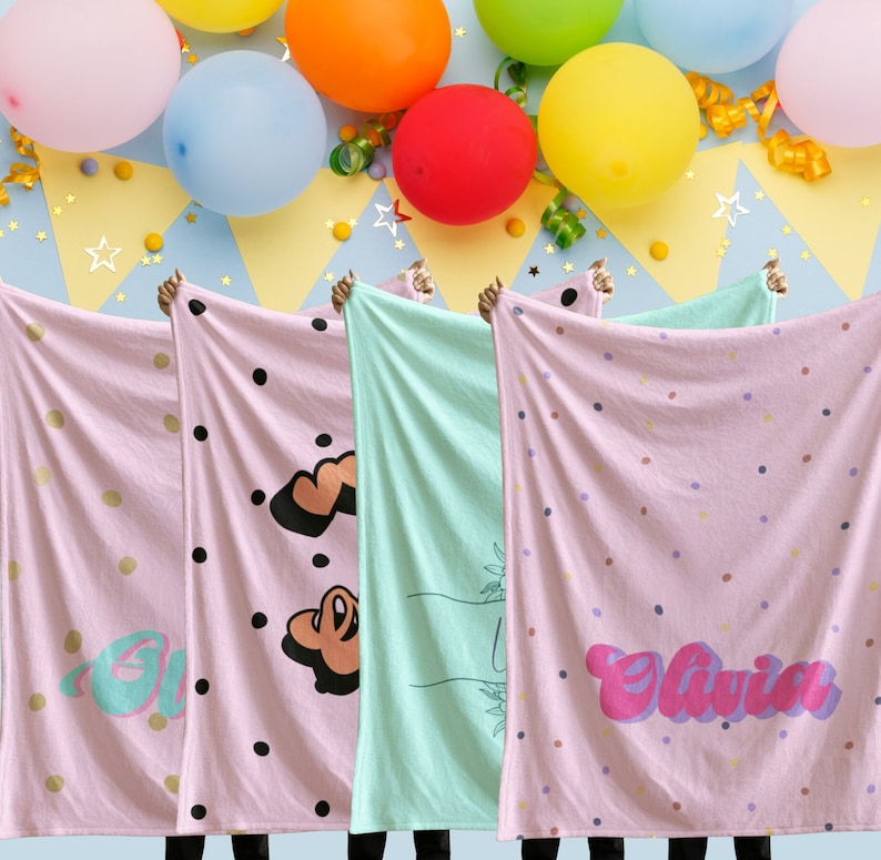 May include: Four pink and white blankets with different designs. The blankets have black polka dots, a heart, a hand with a plant, and the name "Olivia" in pink and purple letters.