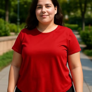 May include: A woman wearing a short-sleeved, round-neck red t-shirt and black pants. The clothing is simple and casual, suitable for everyday wear. The background is a blurred outdoor scene with greenery.
