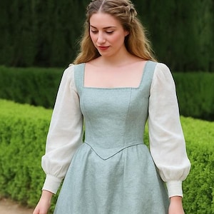 May include: A long, light green dress with a square neckline and long white sleeves. The dress has a fitted bodice and a full skirt. The sleeves are gathered at the wrist. The dress is suitable for historical reenactment or costume events.