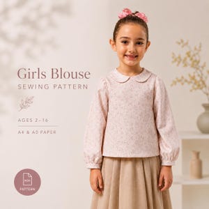 May include: A sewing pattern for a girls blouse featuring a light pink long-sleeved top with a small floral print and a rounded collar. The text reads Girls Blouse SEWING PATTERN, AGES 2-16, A4 & A0 PAPER, and PDF PATTERN. The design includes cuffed sleeves.