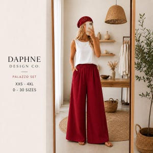 May include: A two-piece palazzo set featuring a sleeveless white top and high-waisted, wide-leg trousers in a deep red color. The set includes a matching red head covering. Text on the left reads DAPHNE DESIGN CO. PALAZZO SET XXS - 4XL 0 - 30 SIZES.