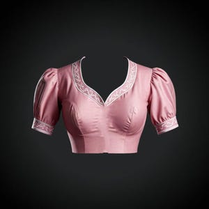 Può includere: Una blusa rosa senza maniche con un collo e polsini ricamati in bianco. La blusa ha una scollatura a cuore e un taglio corto.