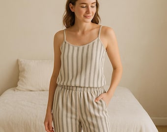 May include: A two-piece pajama set with a camisole top and matching pants. The set features vertical gray and white stripes. The camisole has thin straps and a scoop neckline. The pants have an elastic waistband and a relaxed fit.