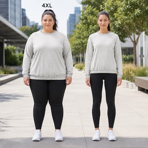 Op de afbeelding: Twee mensen in bijpassende sportoutfits. Beide dragen lichtgrijze sweatshirts met zwarte leggings en witte sneakers. Eén persoon draagt maat 4XL en de ander maat S.