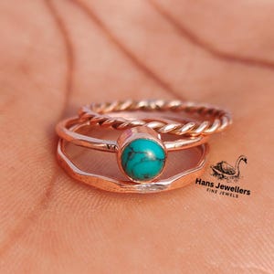 May include: A set of three rose gold rings. One ring features a turquoise stone, another has a twisted design, and the third has a unique openwork shape. The rings are displayed on a skin-toned background.