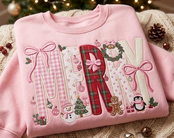 May include: A light pink sweatshirt featuring the word MERRY in large, decorative letters. The letters are filled with pink gingham, red and green plaid, and white polka dot patterns, accented with embroidered bows, a snowman, and a penguin.