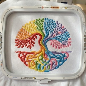 Könnte beinhalten: Ein farbenfrohes, gesticktes Baumdesign mit einem Regenbogen von Farben von Rot bis Lila, wird in einem Stickrahmen gezeigt. Die Äste und Wurzeln des Baumes sind aufwendig detailliert und erzeugen ein lebendiges und auffälliges Bild.