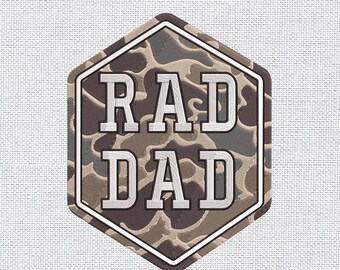 May include: A hexagonal patch with the words "RAD DAD" in bold, white letters. The patch has a camouflage pattern in shades of brown, gray, and green. A white border surrounds the design, set against a textured, off-white background.