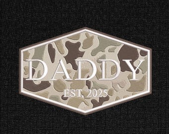 May include: A patch with a camouflage pattern in shades of brown, tan, and green. The word "DADDY" is embroidered in white, with "EST. 2025" below. The patch has a hexagonal shape with a brown border, set against a black textured background.