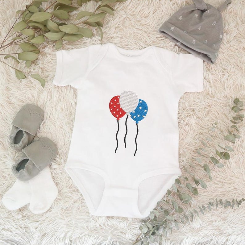 Peut inclure: Body b&eacute;b&eacute; blanc avec un motif de ballons rouges, blancs et bleus. Les ballons sont d&eacute;cor&eacute;s d'&eacute;toiles et de points. Un chapeau de b&eacute;b&eacute; gris et des chaussures de b&eacute;b&eacute; grises sont &eacute;galement dans l'image.