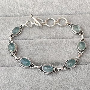 May include: A silver bracelet with a toggle clasp and oval-shaped blue aquamarine stones.