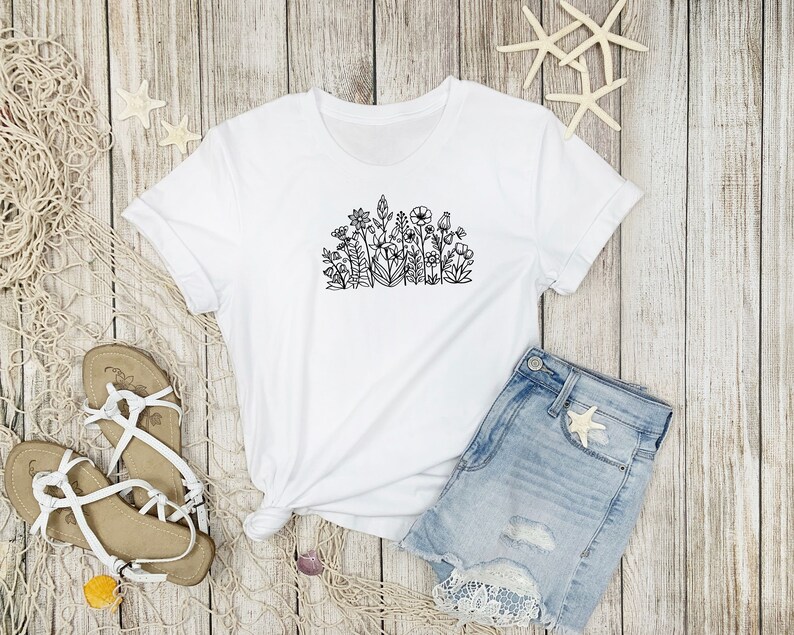 May include: White t-shirt with a black line drawing of a cluster of flowers on the front.