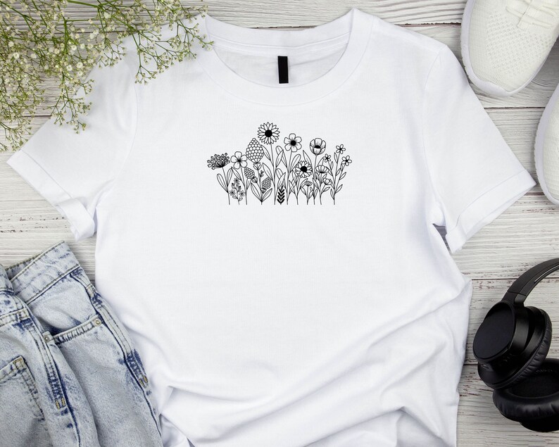 May include: White t-shirt with a black line drawing of a cluster of flowers on the front.