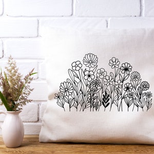 May include: A white pillow with a black line drawing of a garden of flowers. The flowers are stylized and have simple shapes.