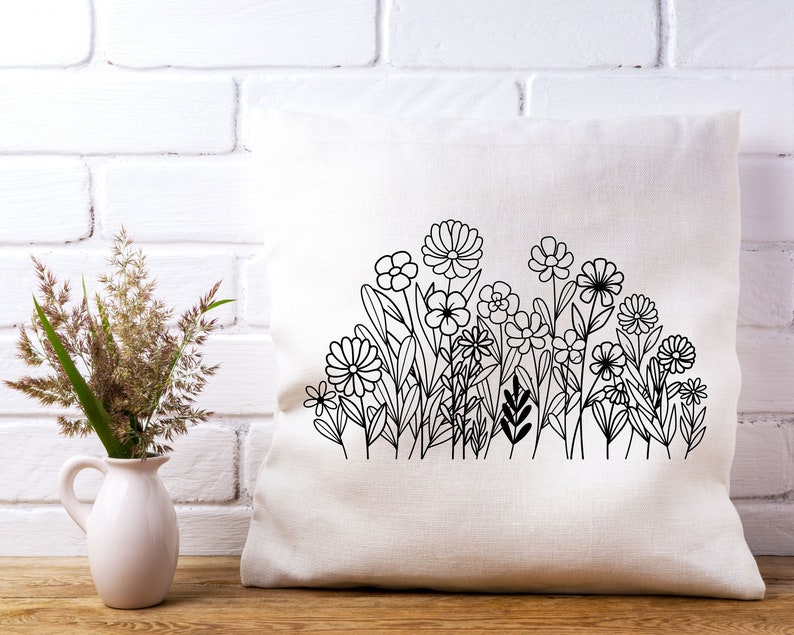 May include: A white pillow with a black line drawing of a garden of flowers. The flowers are stylized and have simple shapes.