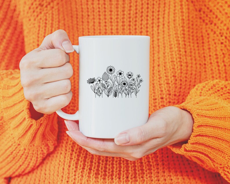 May include: A white ceramic mug with a black line drawing of a cluster of flowers on the front.