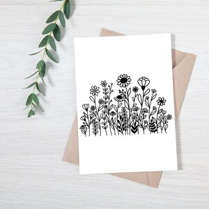 May include: A black and white illustration of a field of wildflowers. The flowers are drawn in a simple, stylized way, with rounded petals and stems.