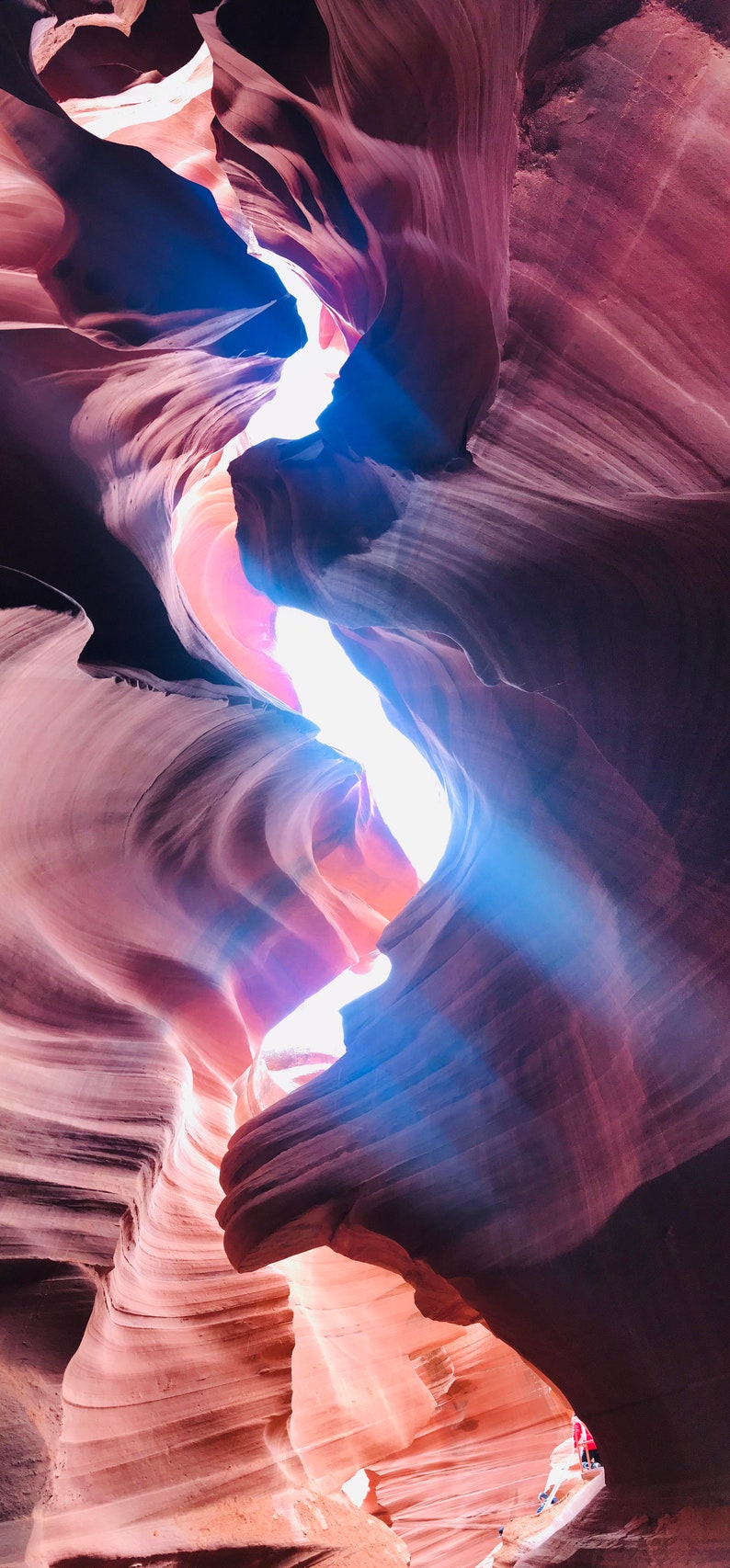 K&ouml;nnte beinhalten: Eine enge Schlucht mit glatten, wirbelnden, roten Felsw&auml;nden. Ein Lichtstrahl scheint durch eine L&uuml;cke im Fels und beleuchtet die Schlucht.