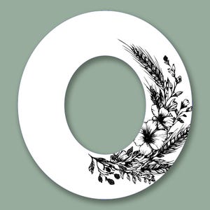 May include: White letter "O" with a floral and wheat design in black ink. The illustration features detailed botanical elements, including flowers, wheat stalks, and leaves, set against a soft green background.