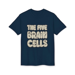 May include: A navy blue t-shirt displaying the text "THE FIVE BRAIN CELLS" in a beige, stylized font. The design incorporates a brain cell graphic with gear and mechanical elements. A casual, science-themed tee.