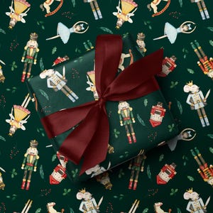 May include: Dark green wrapping paper with a repeating pattern of watercolor illustrations of nutcrackers, mice, ballerinas, and rocking horses. A wrapped gift with a burgundy bow is in the center.