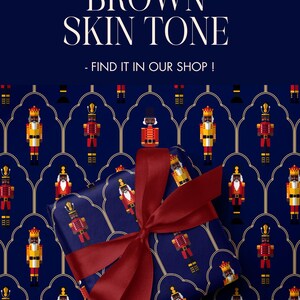 May include: A wrapped gift with a dark blue background featuring a pattern of toy soldiers. The gift is tied with a burgundy ribbon. The text "ALSO AVAILABLE WITH BROWN SKIN TONE - FIND IT IN OUR SHOP!" is displayed at the top.