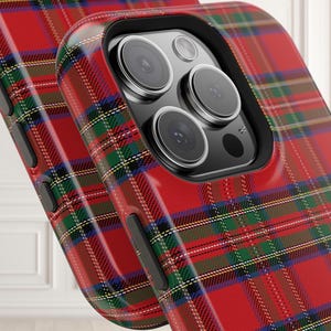 May include: Close-up of two phone cases with a red, green, blue, and white plaid pattern. The cases have a glossy finish and a black camera lens cutout. The phone cases are a protective accessory.