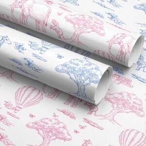 May include: Two rolls of white wrapping paper with a repeating pattern of pink and blue safari animals, trees, hot air balloons, and clouds. The illustrations include elephants, giraffes, and trees. The paper is rolled up, showing the pattern on the surface.