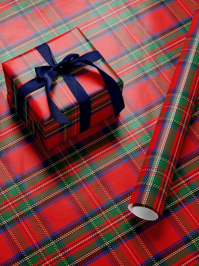 May include: A wrapped gift box and a roll of wrapping paper with a red plaid pattern. The gift box is tied with a navy blue ribbon. The plaid design includes red, green, blue, and white lines.