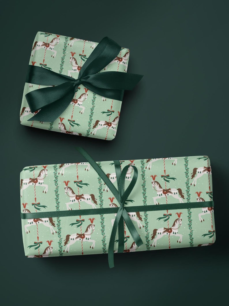 May include: Two wrapped gifts with green ribbon. The wrapping paper has a light green background with a repeating pattern of carousel horses, red and green accents, and vertical lines of greenery. The gifts are on a dark green background.