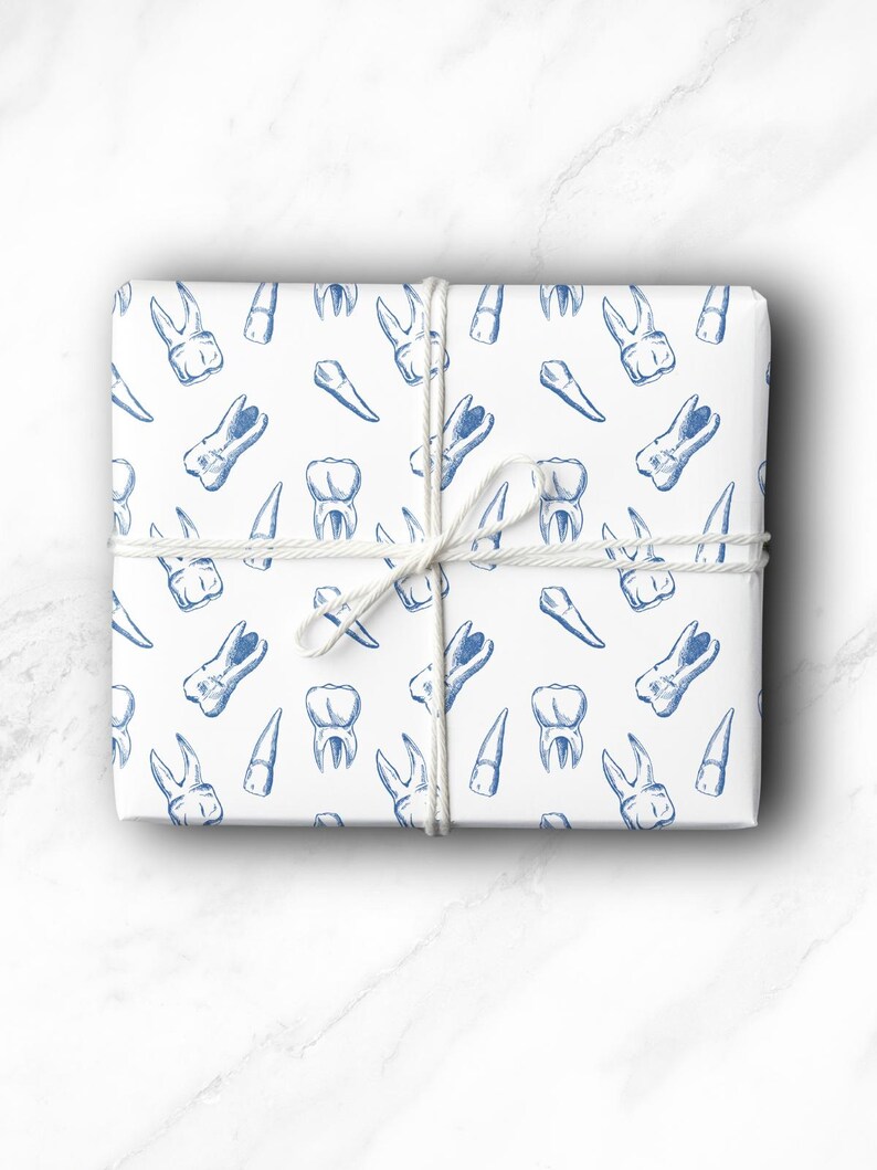 May include: A wrapped gift with white paper featuring a blue illustration of teeth. The gift is tied with white twine. The teeth illustrations include molars, incisors, and premolars.
