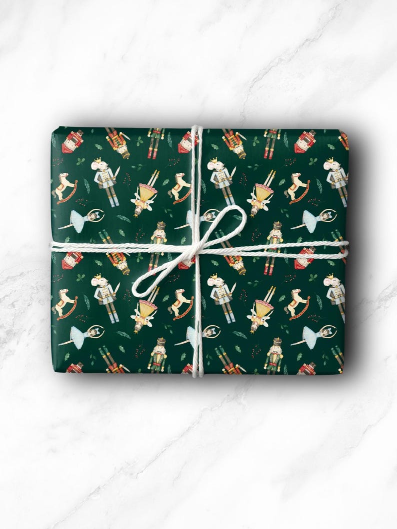 May include: A wrapped gift with a festive green paper featuring a repeating pattern of nutcrackers, rocking horses, ballerinas, and other holiday-themed illustrations. The gift is tied with white twine.