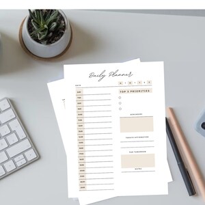 May include: A white daily planner with a brown header that says "Daily Planner". The planner has sections for date, top 3 priorities, reminders, today's affirmation, for tomorrow, and notes.