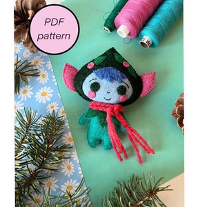 May include: A felt craft pattern for a blue and green fairy with a red scarf. The pattern is labeled "PDF pattern".